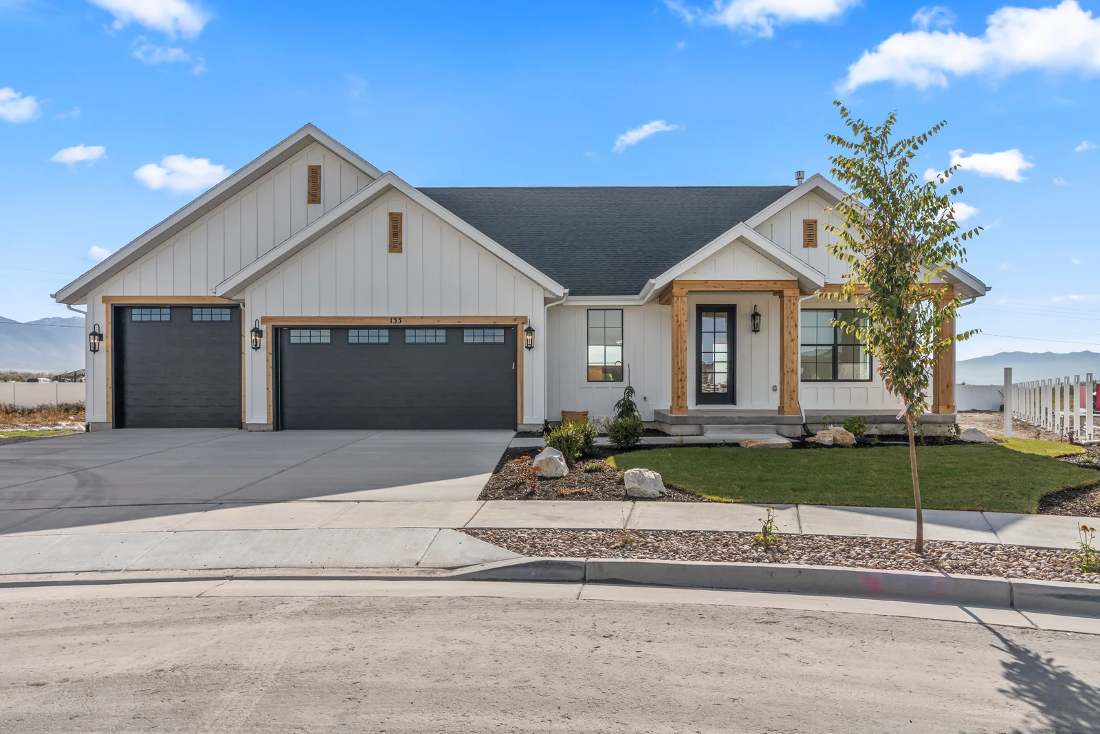 Front exterior with two-car garage, entry porch, paved drive, and planted front bed at Chestnut MW311, Stansbury Park.