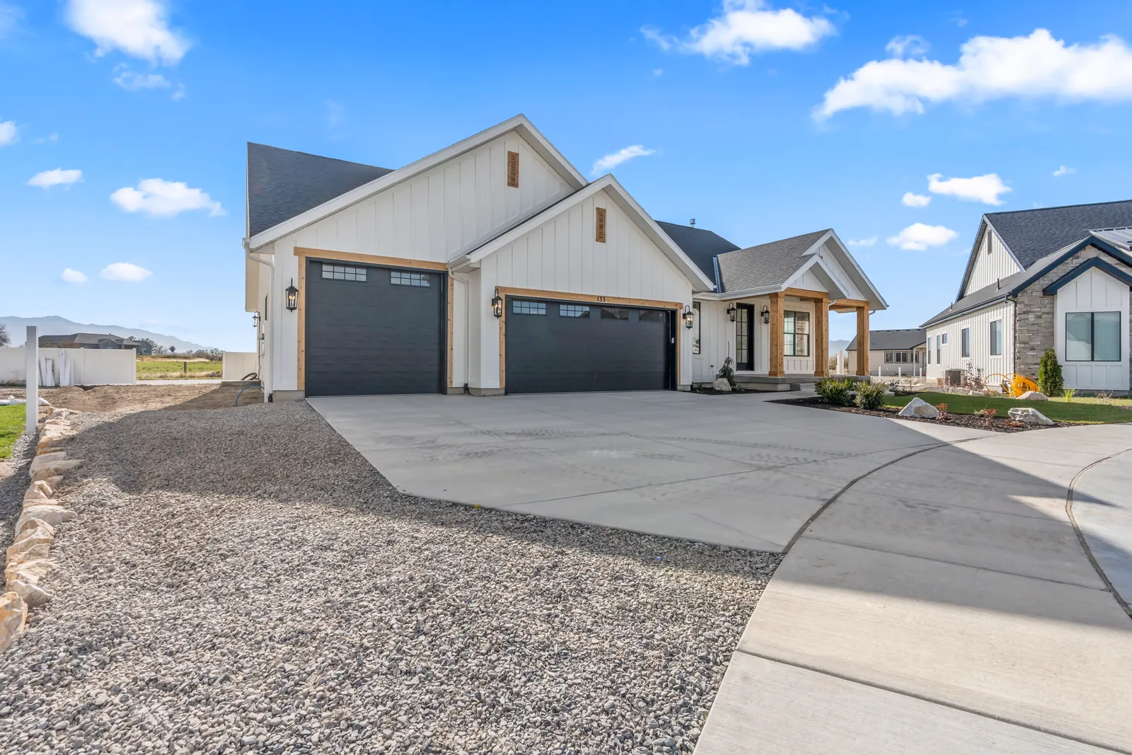Angled front view showing the garage, concrete drive, entry porch, and neighboring homes at Chestnut MW311, Stansbury Park.