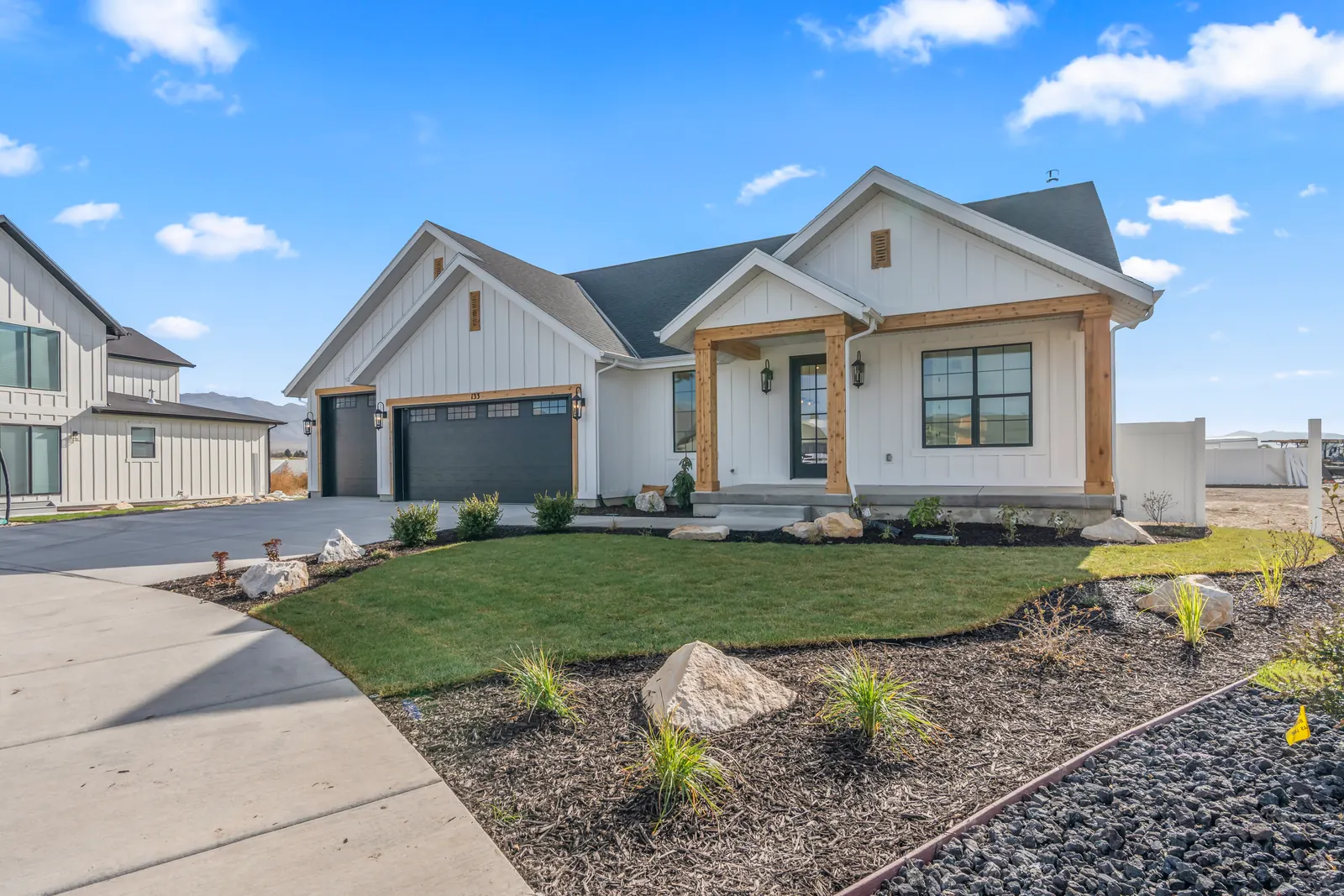 Front façade with garage, covered entry, lawn, and newly planted landscape bed at Chestnut MW311, Stansbury Park.