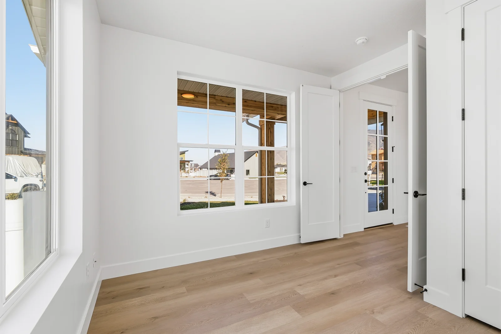 Empty room with wood-look flooring, glass-paneled interior doors, and windows facing the front at Chestnut MW311, Stansbury Park.