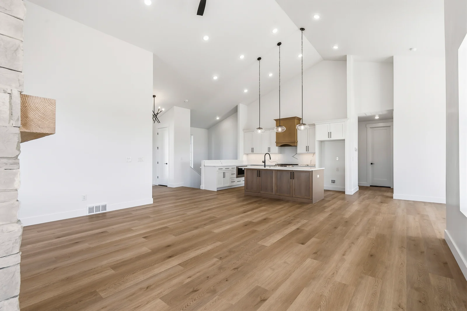 Open main living area connecting the kitchen island, dining space, and stone fireplace at Chestnut MW311, Stansbury Park.