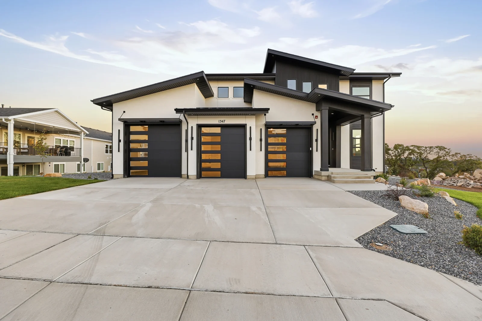 Front exterior with dark trim, two garage doors, concrete driveway, and landscaped rock beds in Hawthorne Modern, Ogden.