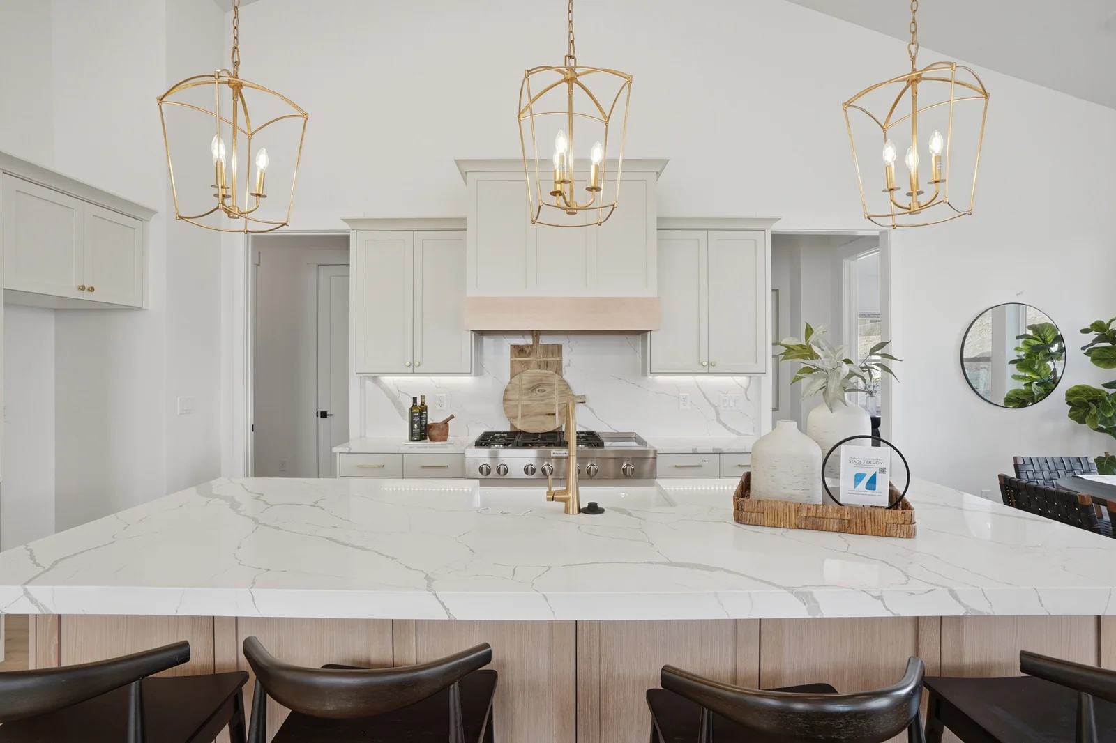 White kitchen island with waterfall-style countertop, pendant lights, stools, and surrounding cabinetry in Olympic BH08, American Fork.
