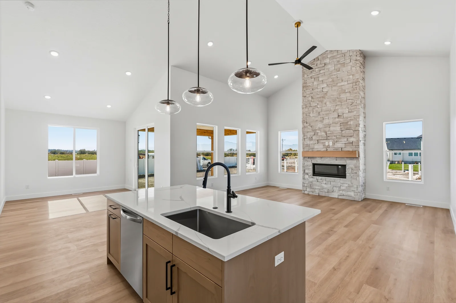 Kitchen island and sink in the foreground, opening toward the bright living room fireplace at Chestnut MW311, Stansbury Park.