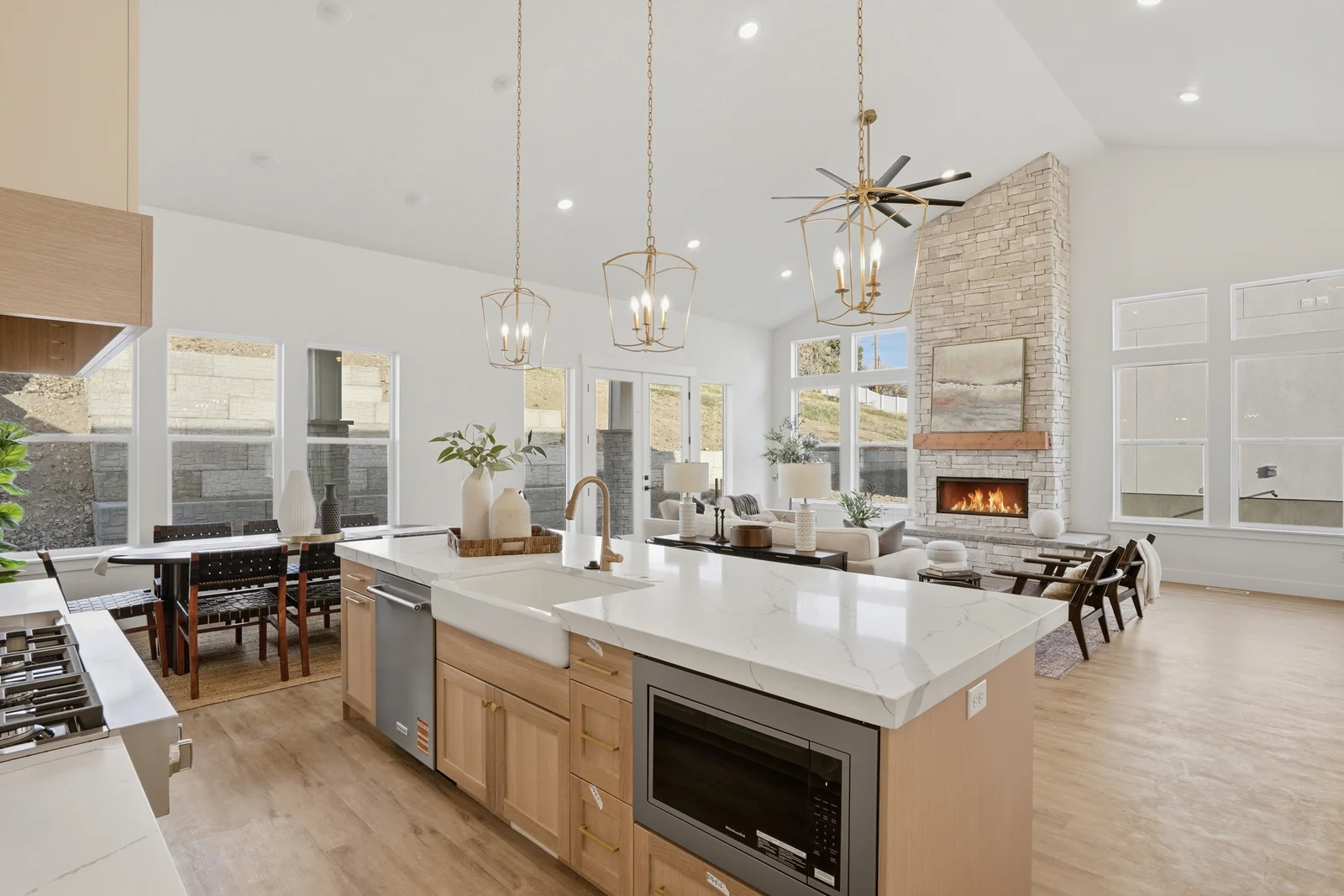 Open kitchen and great room with island seating, dining table, fireplace, and wide-plank flooring in Olympic BH08, American Fork.