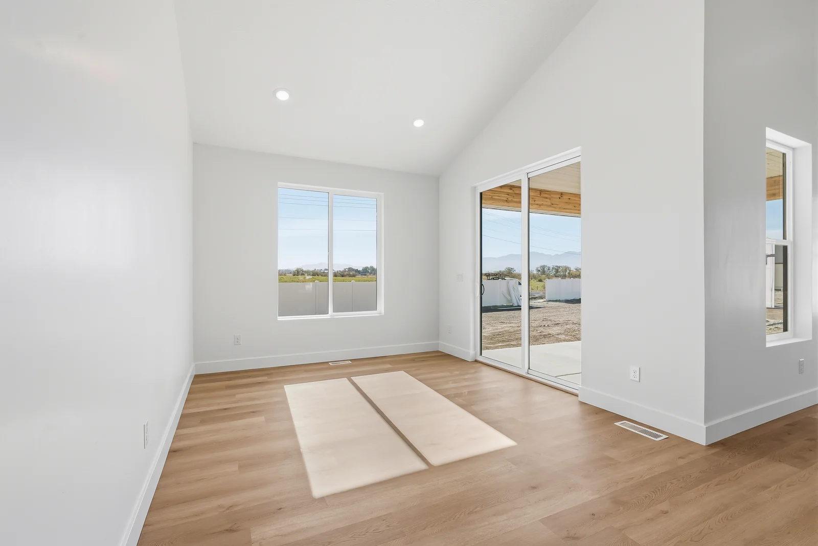Empty bedroom with wood-look flooring, a window, open closet doorway, and bright white walls at Chestnut MW311, Stansbury Park.