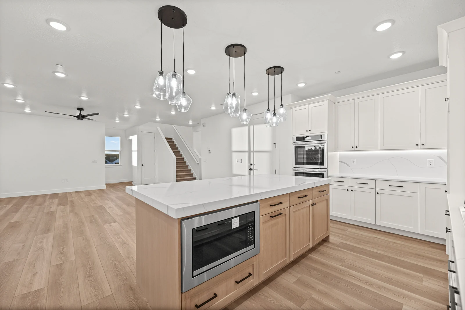 Open kitchen with island, pendant lighting, white cabinetry, and a view toward the living area in Hawthorne Modern, Ogden.