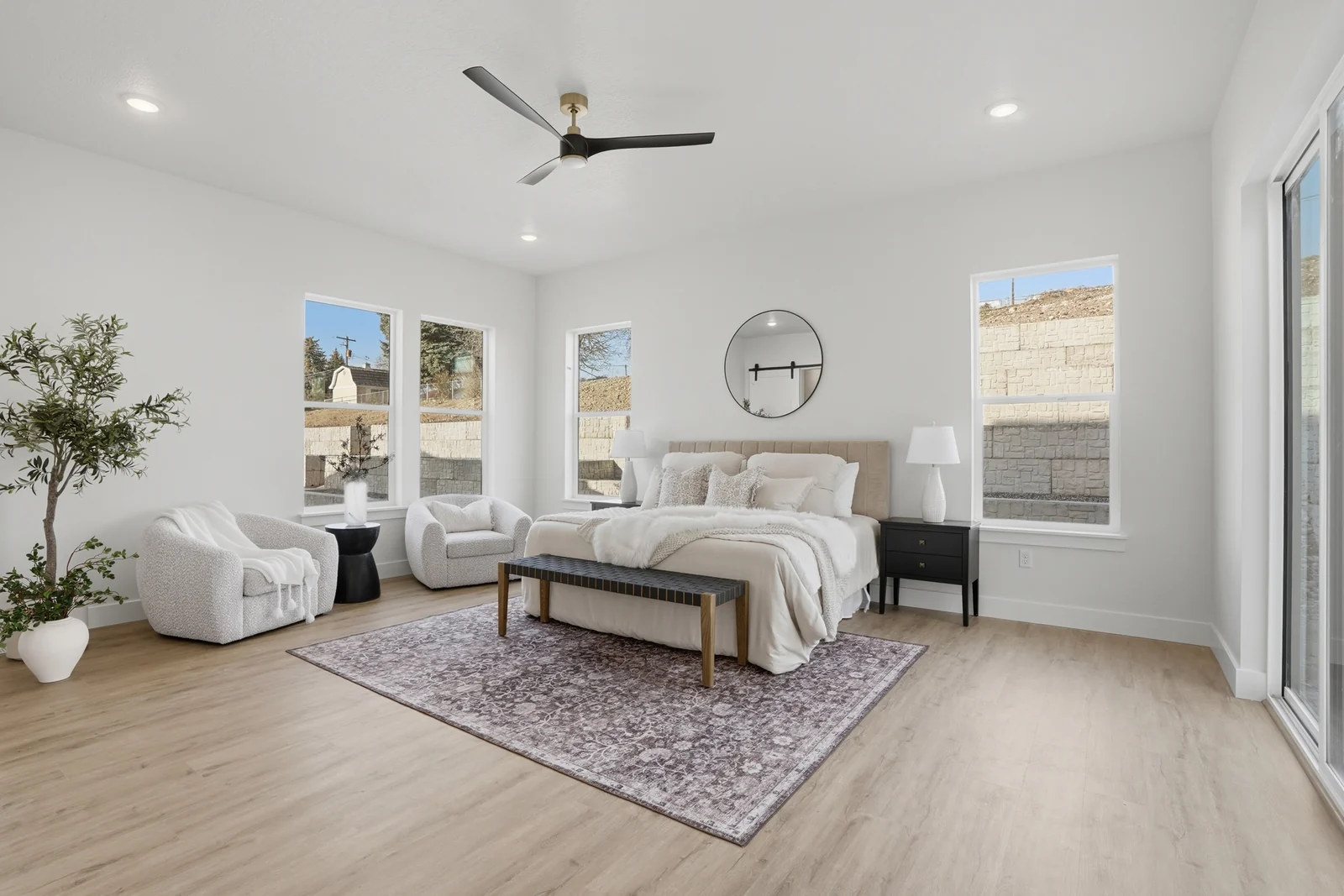 Staged bedroom with bed, rug, ceiling fan, and large windows in Olympic BH08, American Fork.