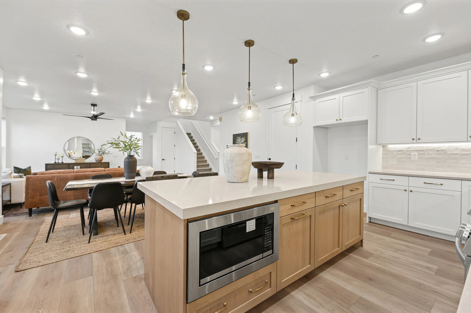 Wood-base kitchen island faces a dining table and adjoining living area in Hawthorne Farmhouse, Ogden.