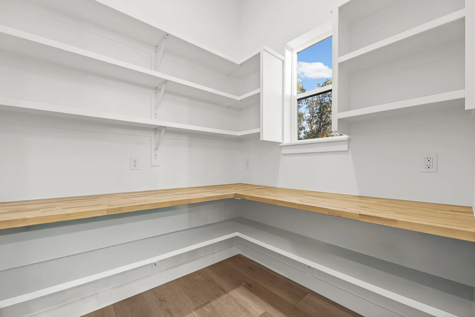 Walk-in pantry with wraparound white shelving, wood-look flooring, and a window in Hawthorne Modern, Ogden.