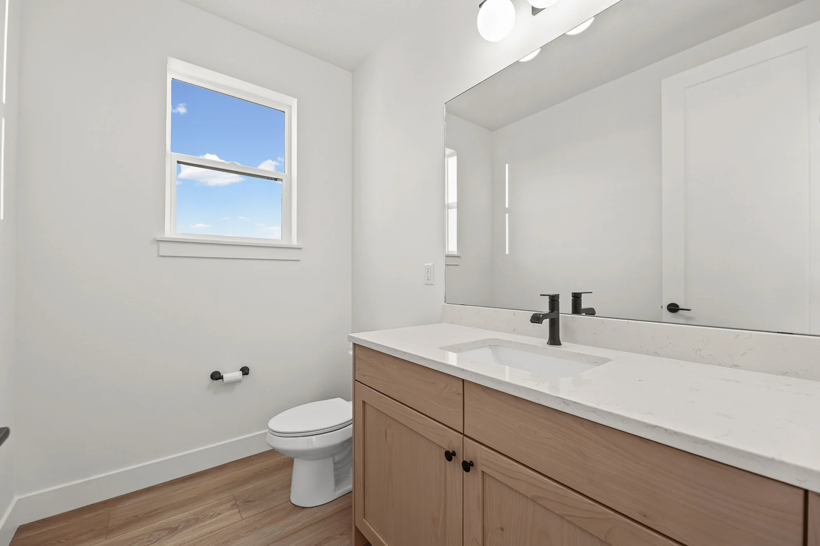 Bathroom with wood double vanity, white countertop, toilet, and window in Hawthorne Modern, Ogden.