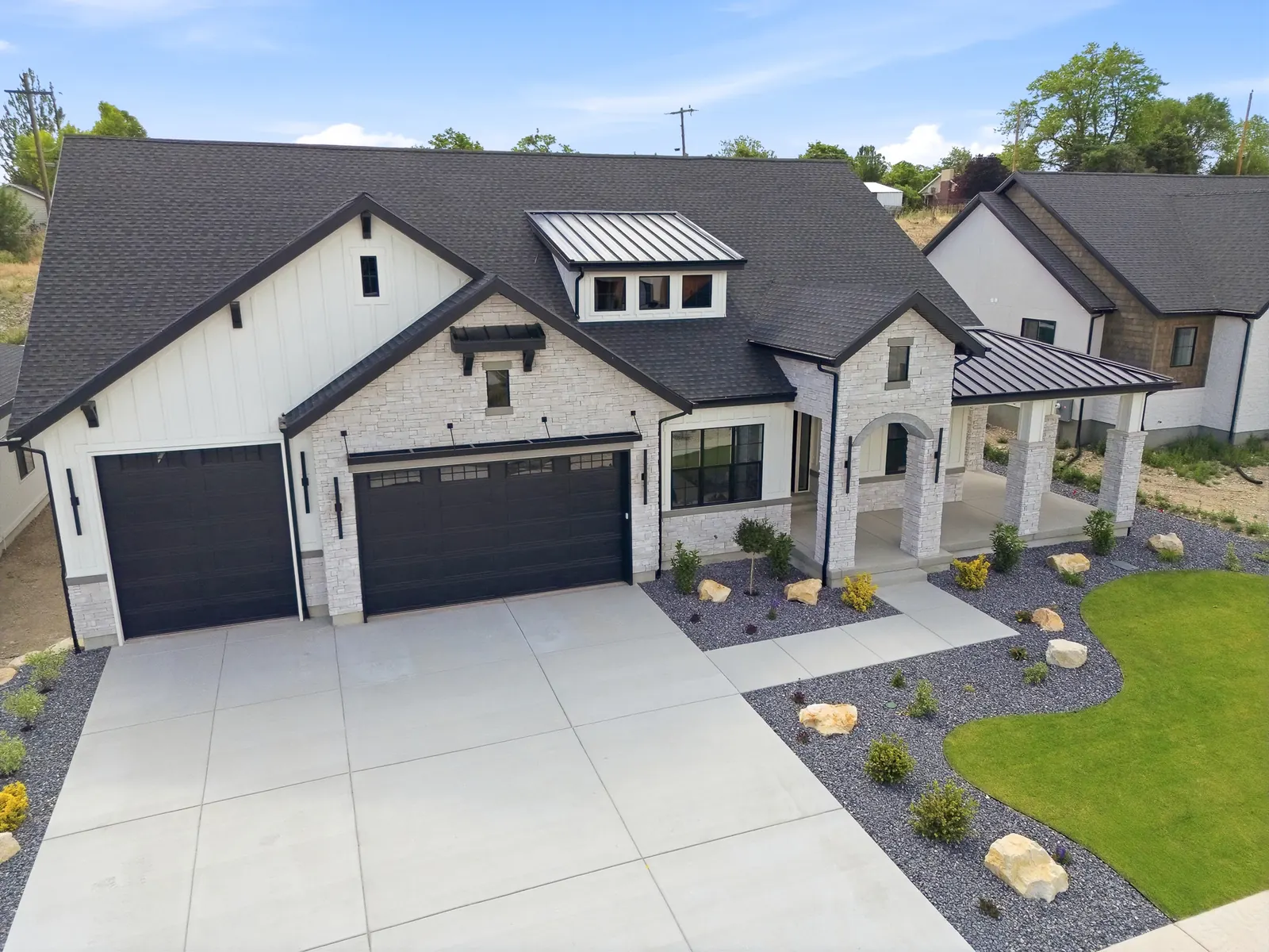 Aerial angle over the front elevation, driveway, garage doors, and surrounding homes in Olympic BH08, American Fork.