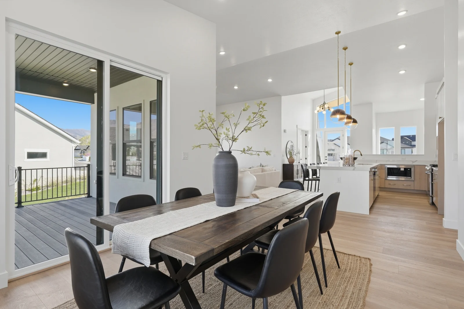 Dining area with a wood table, glass doors, and a connected view into the kitchen in Chestnut Modern MW302, Stansbury Park.