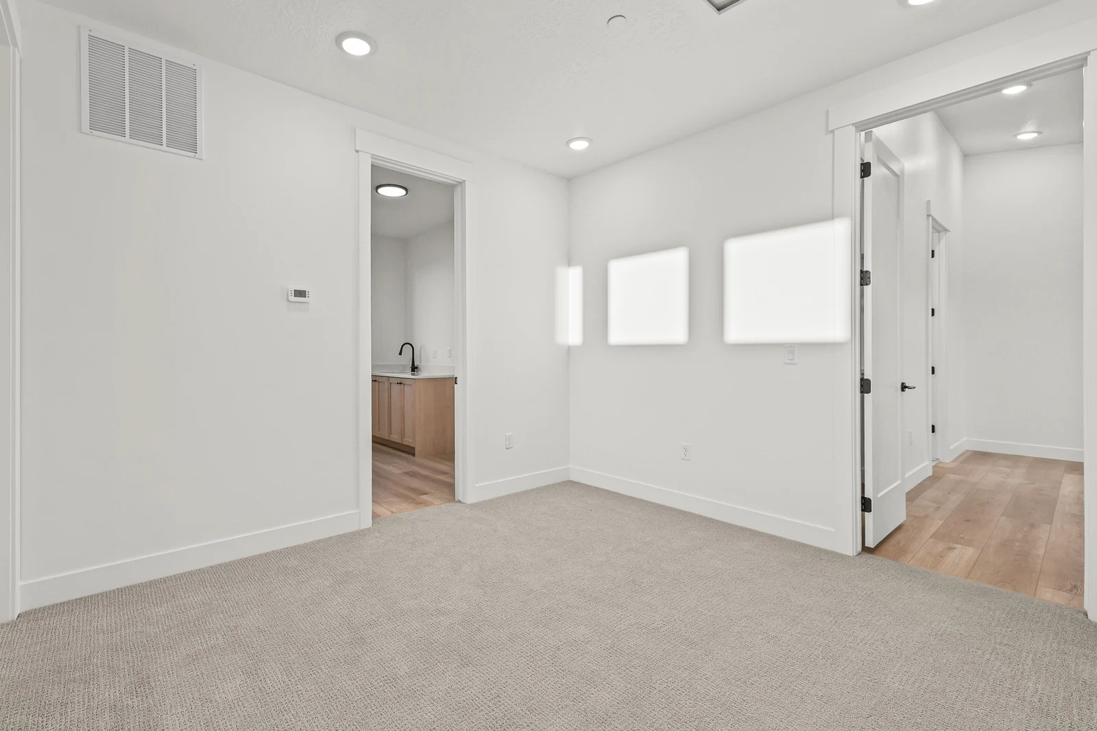 Carpeted upper landing with recessed lights, interior doorways, and wood flooring visible beyond in Hawthorne Modern, Ogden.