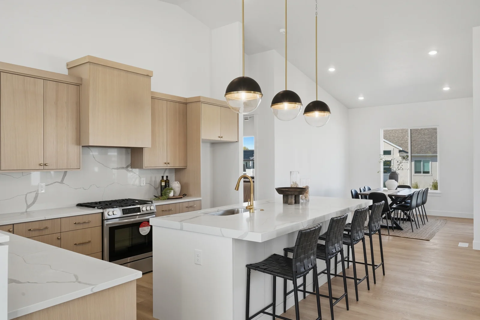 Open kitchen with island seating, pendant lights, range, and adjacent dining table in Chestnut Modern MW302, Stansbury Park.