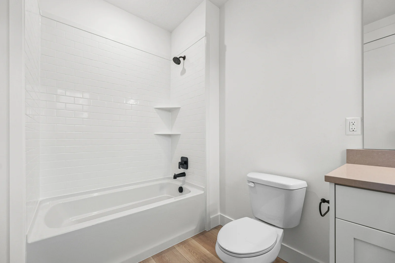 Full bathroom features a white tub-shower combination, vanity, toilet, and pale wood flooring in Hawthorne Farmhouse, Ogden.