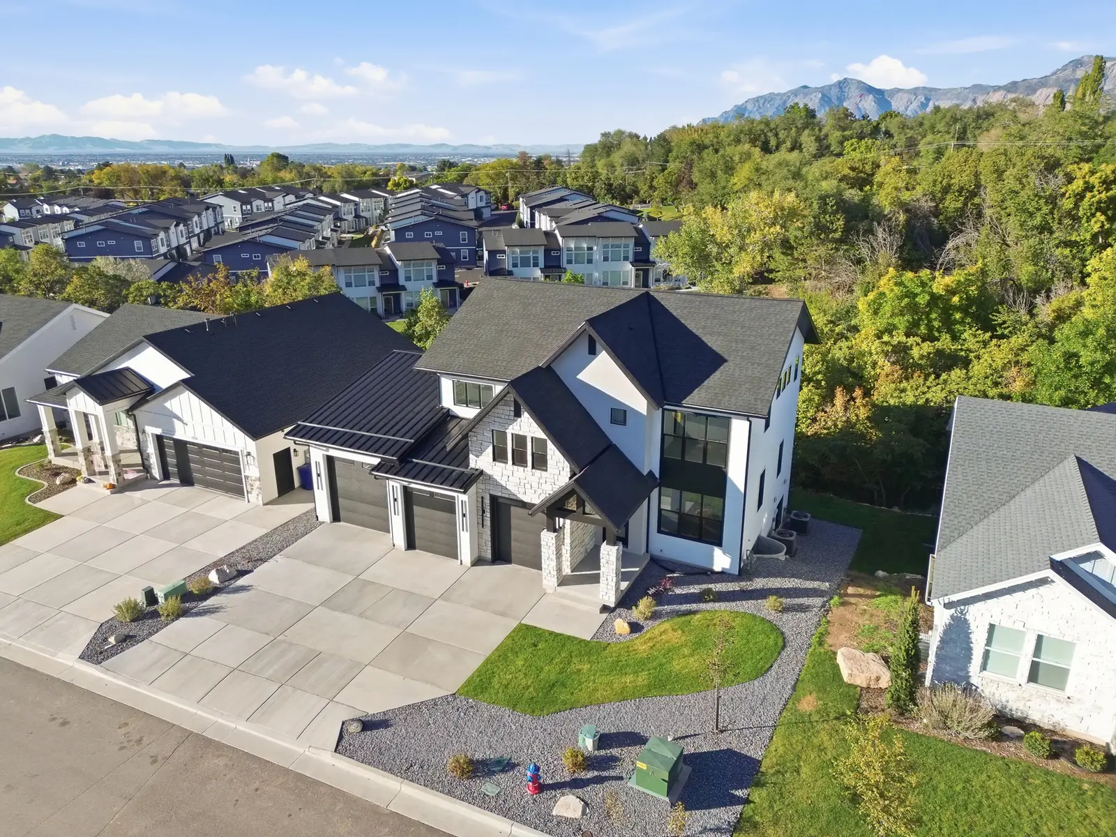 Aerial photo shows the home, driveway, nearby houses, tree-lined slope, and distant landscape in Hawthorne Farmhouse, Ogden.