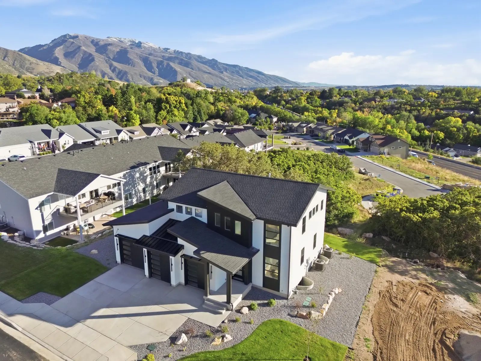Aerial photograph showing the home, neighboring houses, streets, green trees, and mountain backdrop in Hawthorne Modern, Ogden.