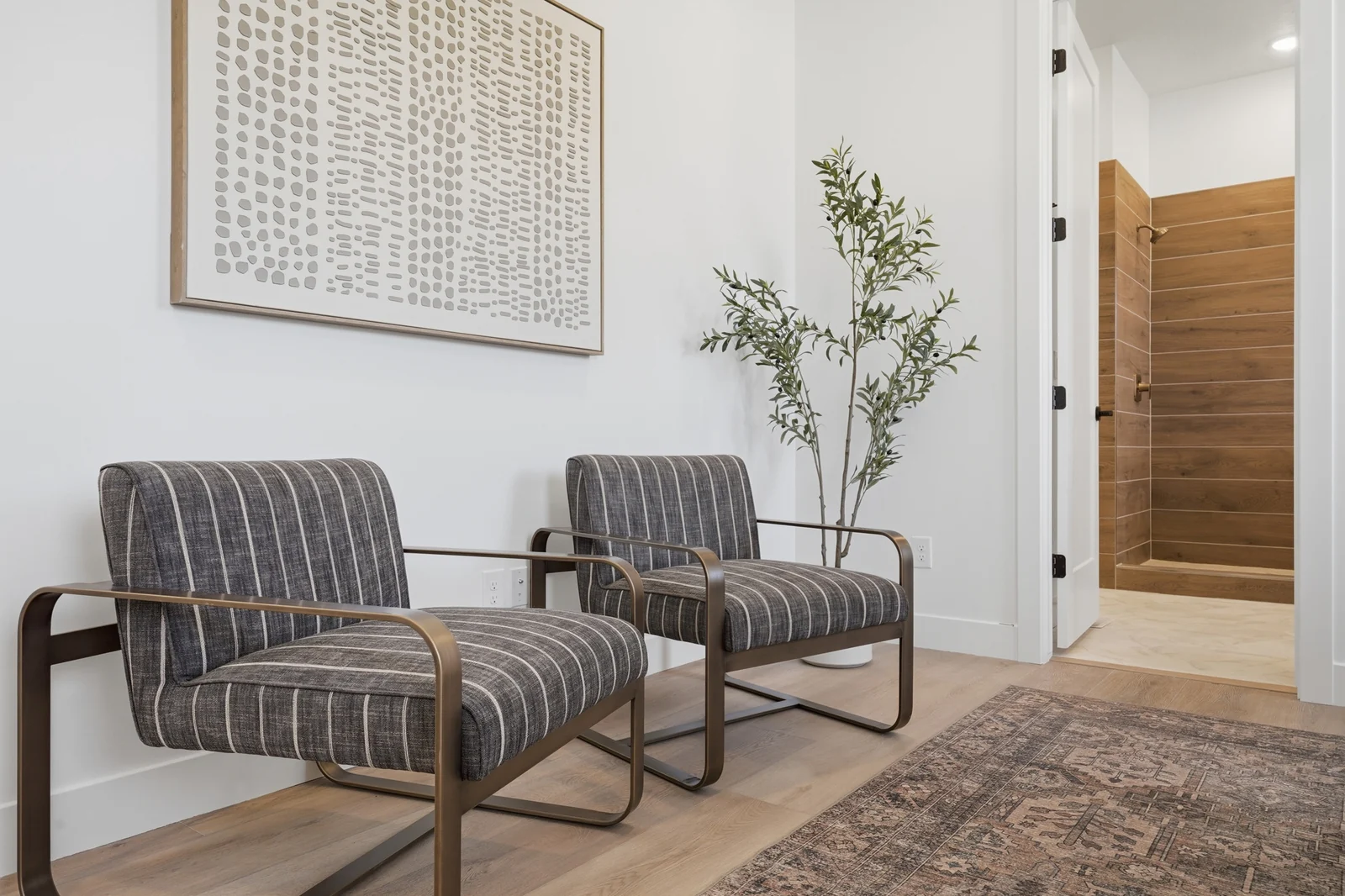 Foyer seating area with two striped chairs, wall art, a rug, and wood entry door in Chestnut Modern MW302, Stansbury Park.