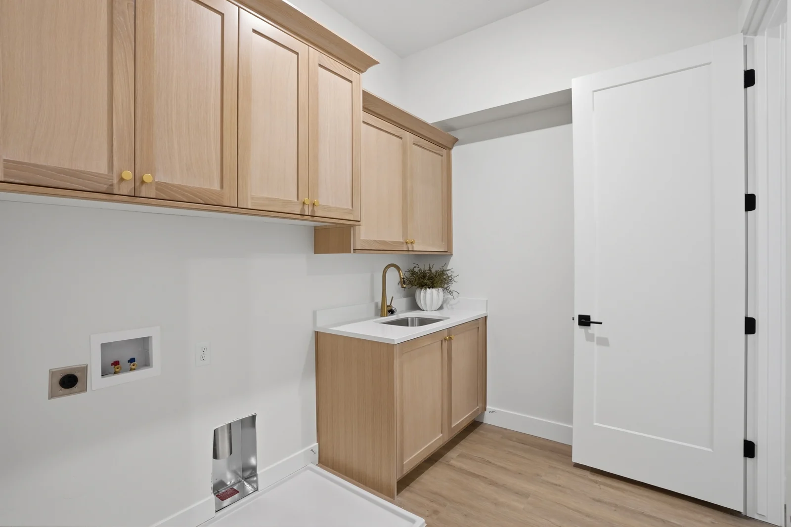 Laundry room with wood cabinetry, utility sink, white walls, and a tiled backsplash in Olympic BH08, American Fork.