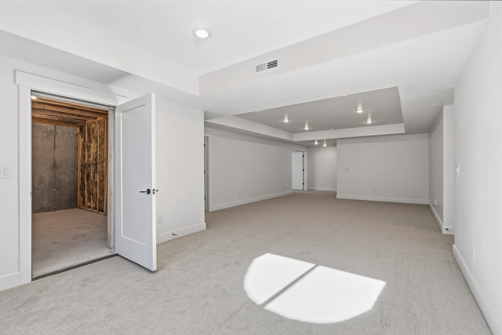 Finished lower-level open room with light carpet, recessed ceiling lights, and an open doorway at Chestnut MW311, Stansbury Park.