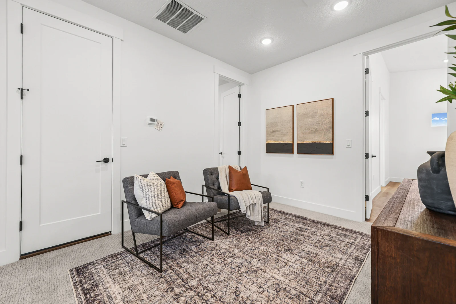 Entry sitting area has two chairs, patterned rug, double doors, and pale wood flooring in Hawthorne Farmhouse, Ogden.