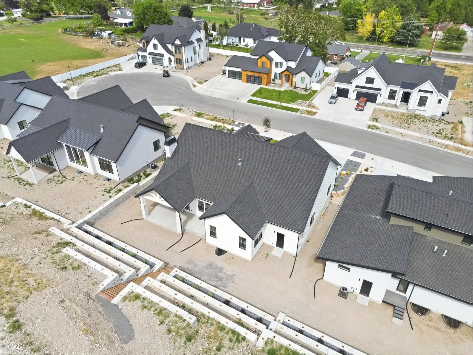 Aerial rear view of the home, covered patio, terraces, and adjoining neighborhood in Olympic BH08, American Fork.