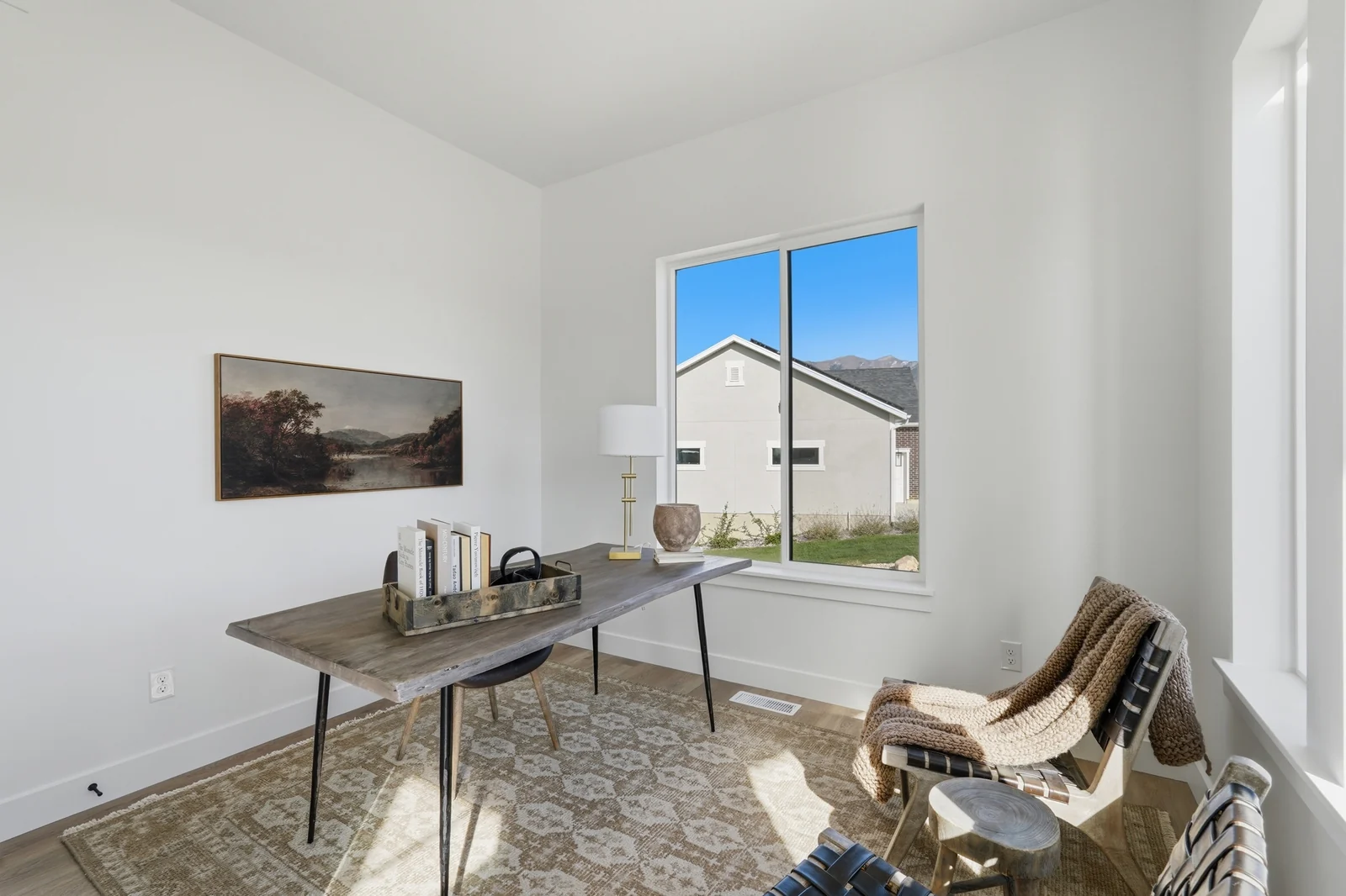 Staged home office with desk, chair, wall art, window, and upholstered accent chair in Chestnut Modern MW302, Stansbury Park.