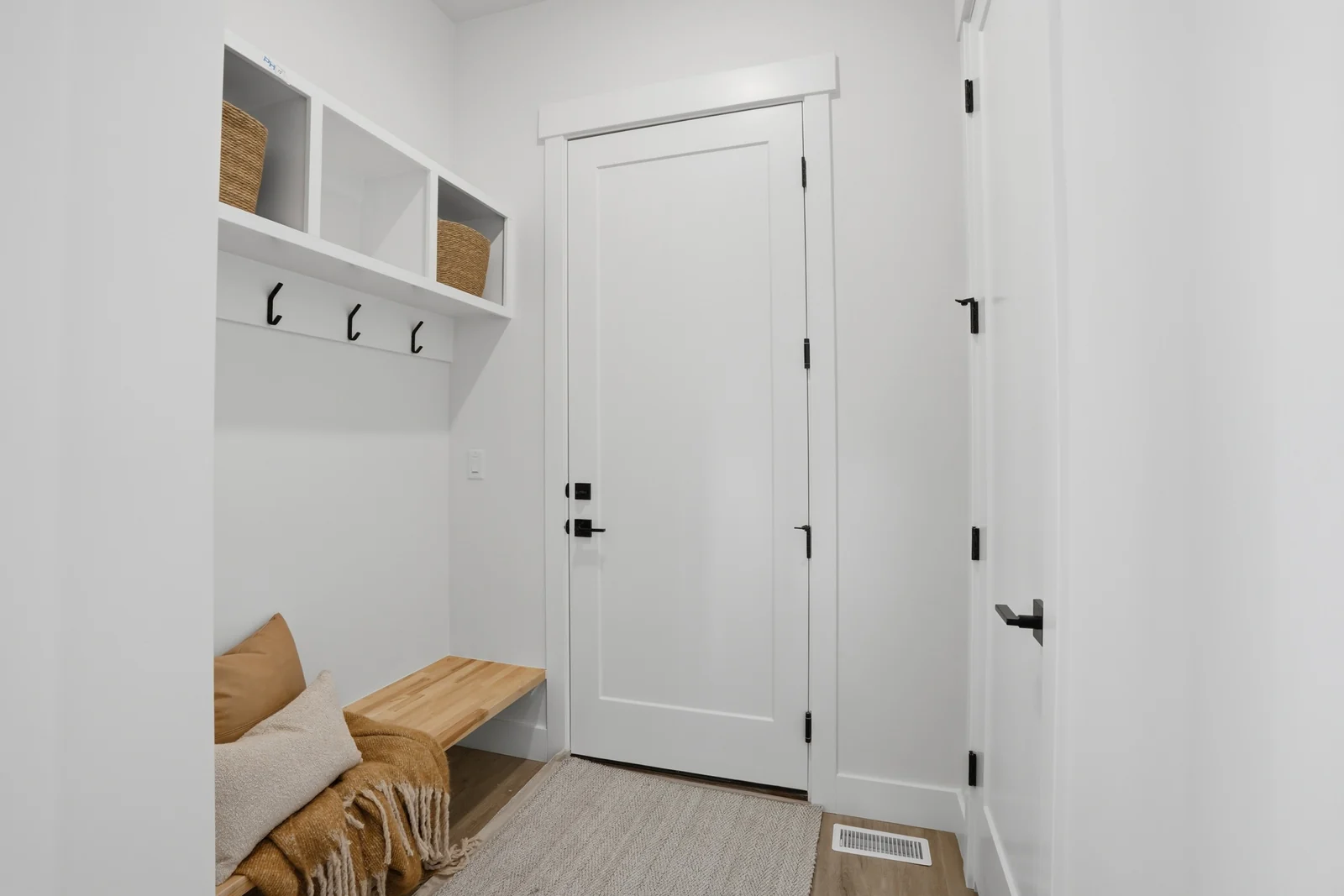 Mudroom with built-in bench, wall hooks, upper cubbies, and a nearby interior door in Olympic BH08, American Fork.