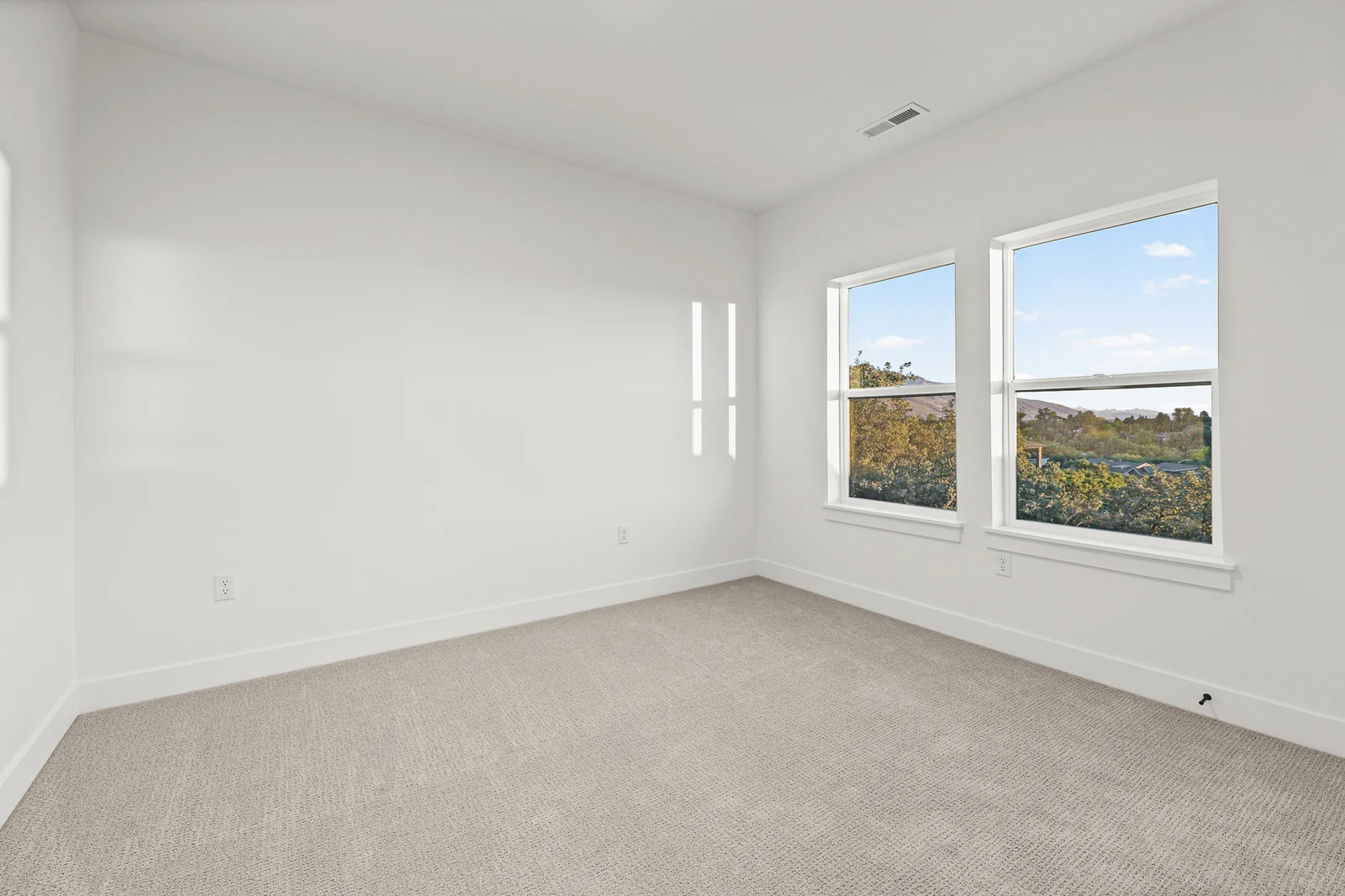 Unfurnished carpeted bedroom with two windows, white walls, recessed light, and wide baseboards in Hawthorne Modern, Ogden.