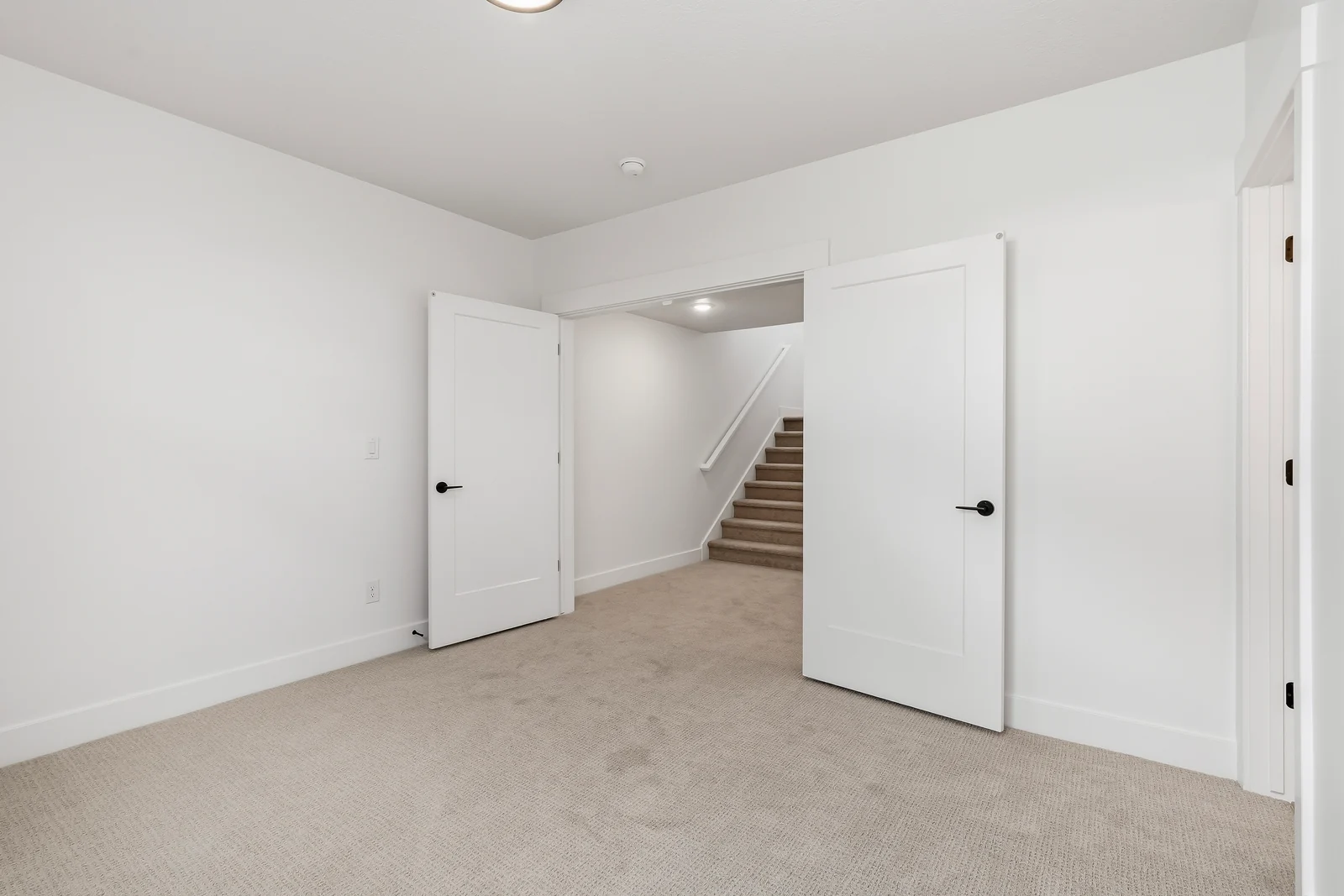 Carpeted lower-level room with a window, closet doors, open doorway, and stairway beyond at Chestnut MW311, Stansbury Park.