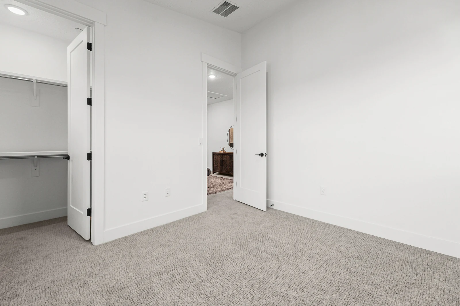 Carpeted bedroom shows a window, double closet doors, and an open doorway in Hawthorne Farmhouse, Ogden.