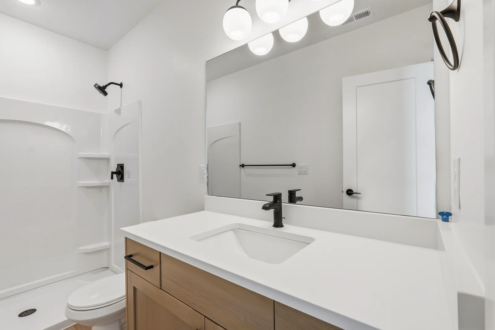 Lower-level bathroom with single vanity, black faucet, mirror, toilet, and white shower surround at Chestnut MW311, Stansbury Park.