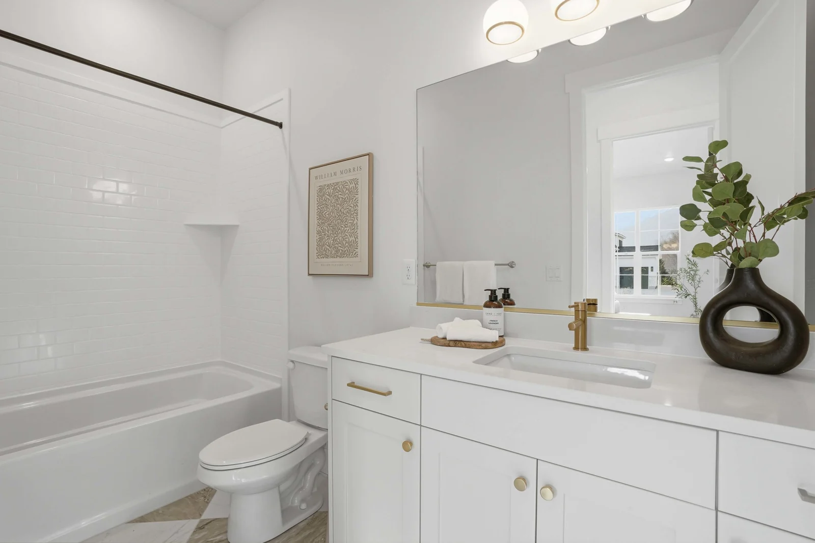 Bathroom vanity with white cabinet, framed mirror, gold-toned faucet, and bathtub edge in Olympic BH08, American Fork.