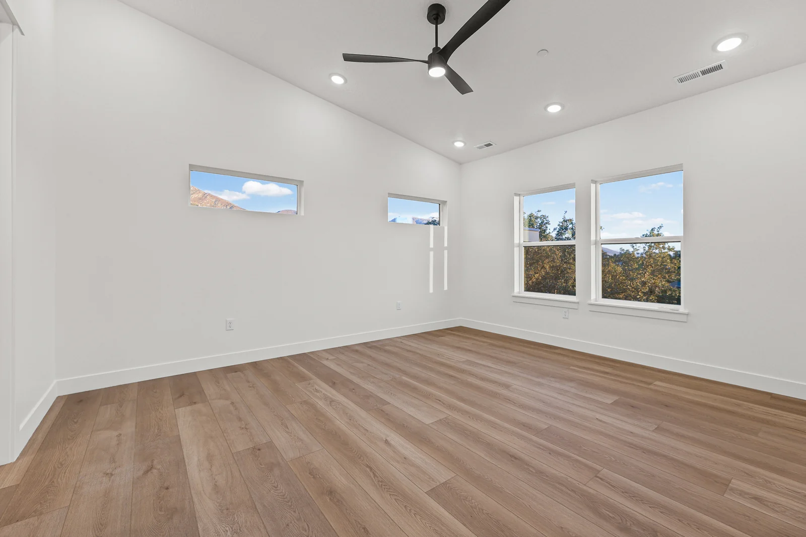 Unfurnished bedroom with wood-look flooring, ceiling fan, high window, and two large windows in Hawthorne Modern, Ogden.