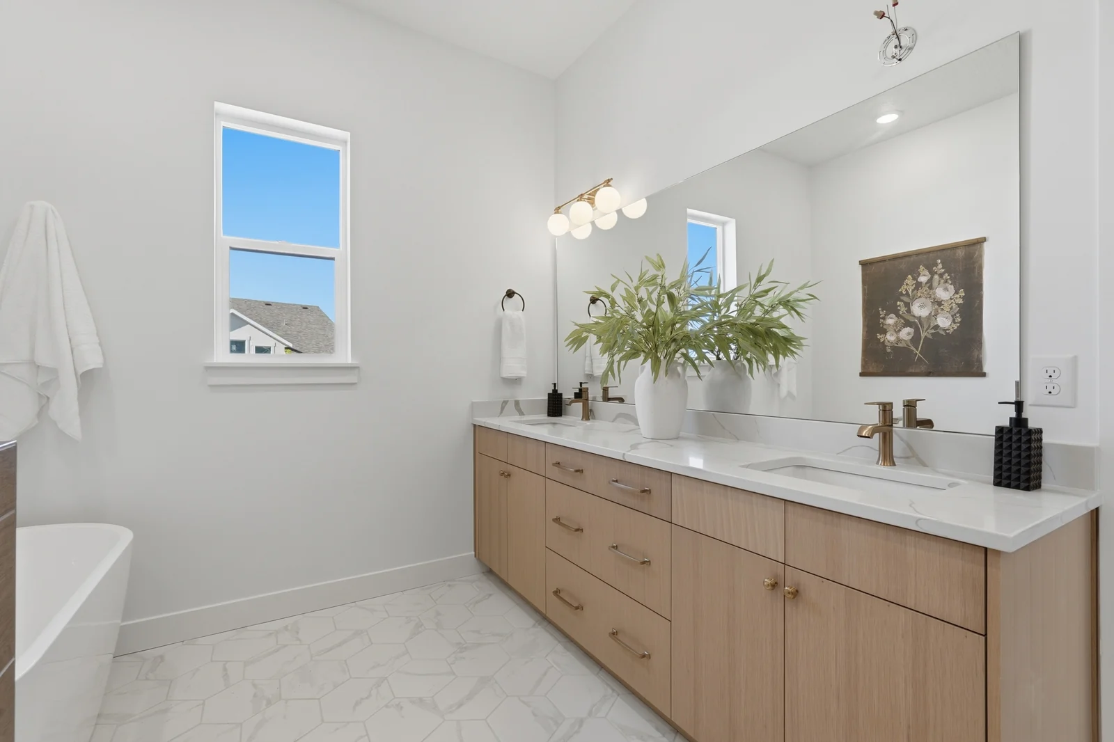 Bathroom with a long double vanity, large mirror, wood cabinetry, and freestanding tub in Chestnut Modern MW302, Stansbury Park.