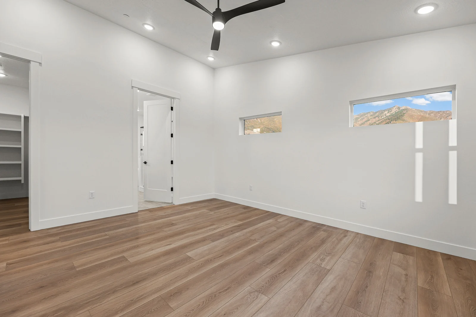 Unfurnished bedroom with wood-look flooring, ceiling fan, high horizontal window, and double doors in Hawthorne Modern, Ogden.