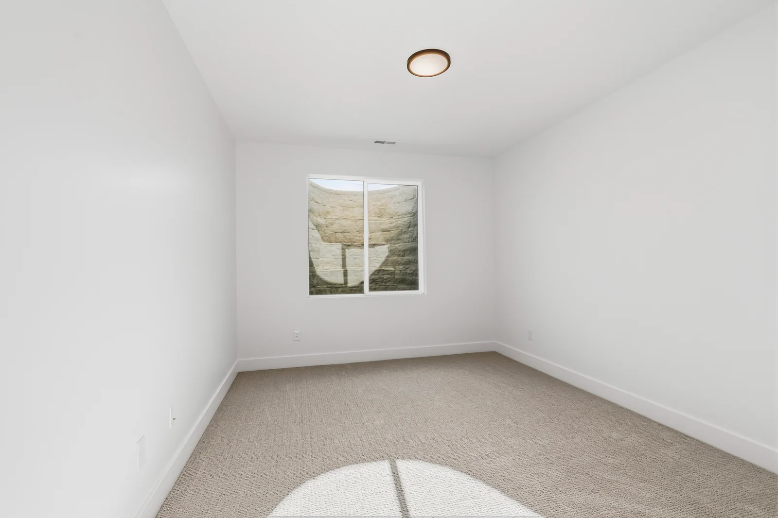 Bright carpeted lower-level bedroom with window, double closet doors, and a doorway toward the hall at Chestnut MW311, Stansbury Park.