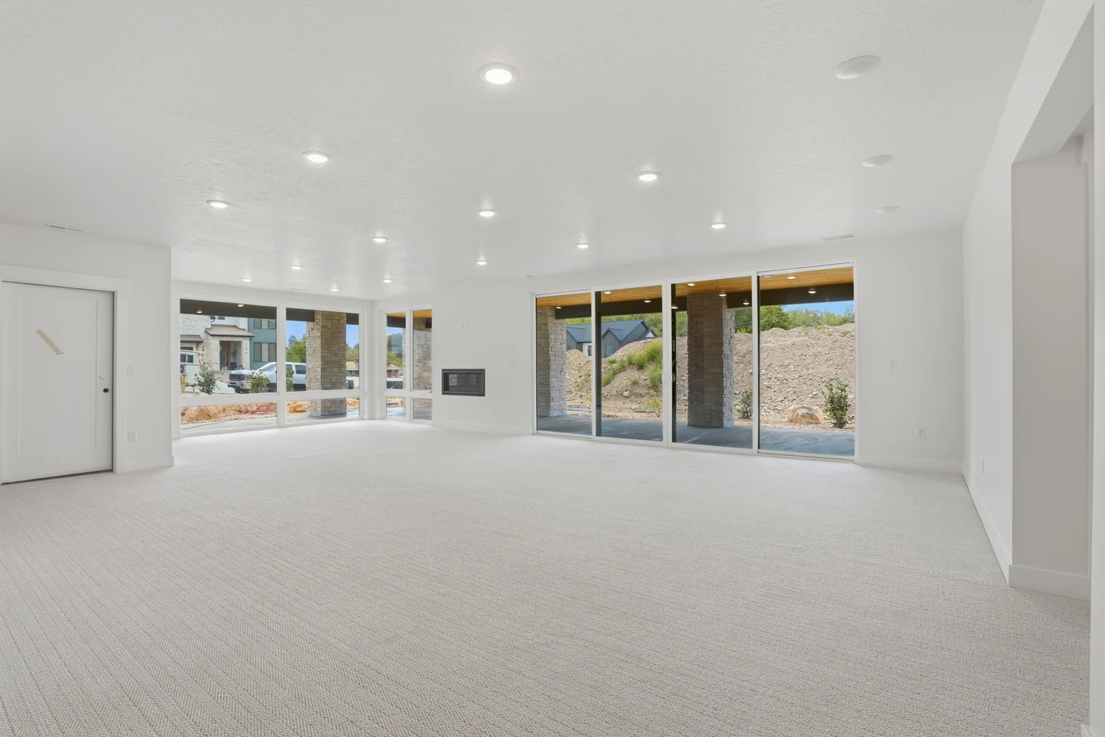 Open lower-level living area with pale carpet, a linear fireplace, recessed lights, and sliding glass doors to the exterior in the Denali model, American Fork.