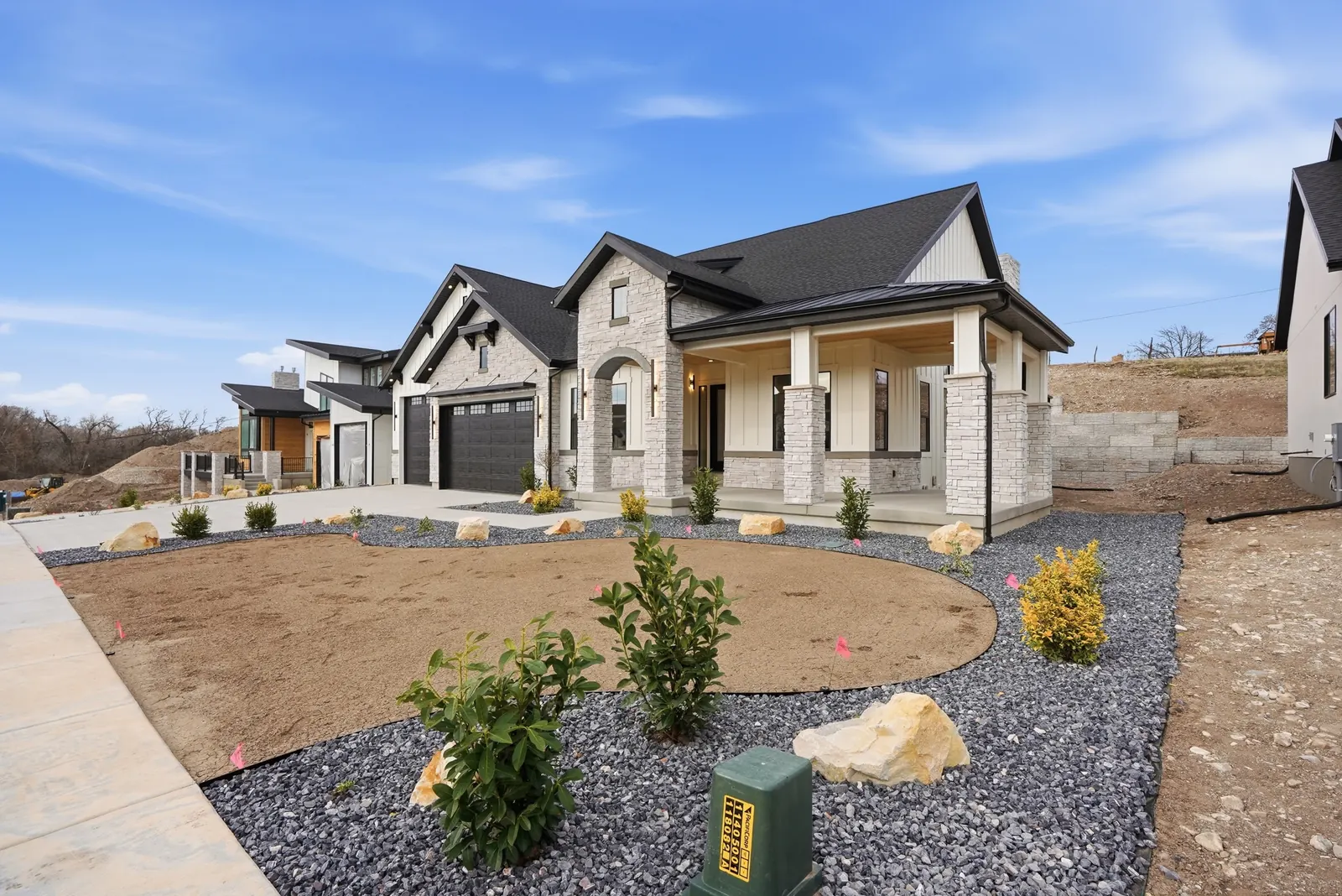 Wide front view of the stone-and-siding facade, landscaped edge, garage doors, and driveway in Olympic BH08, American Fork.