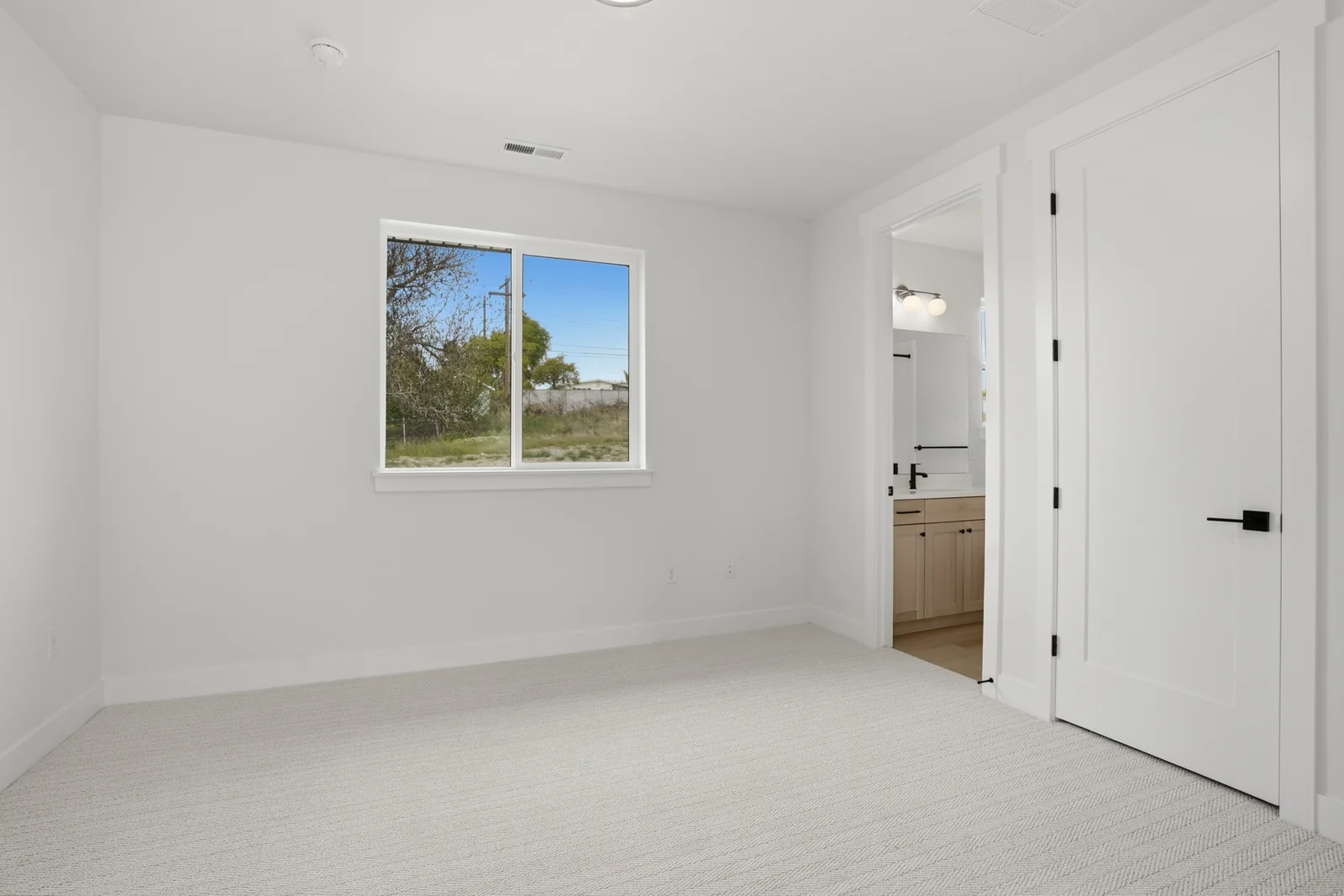 Unfurnished bedroom with pale carpet, recessed lighting, a single window, and multiple white interior doors in the Denali model, American Fork.