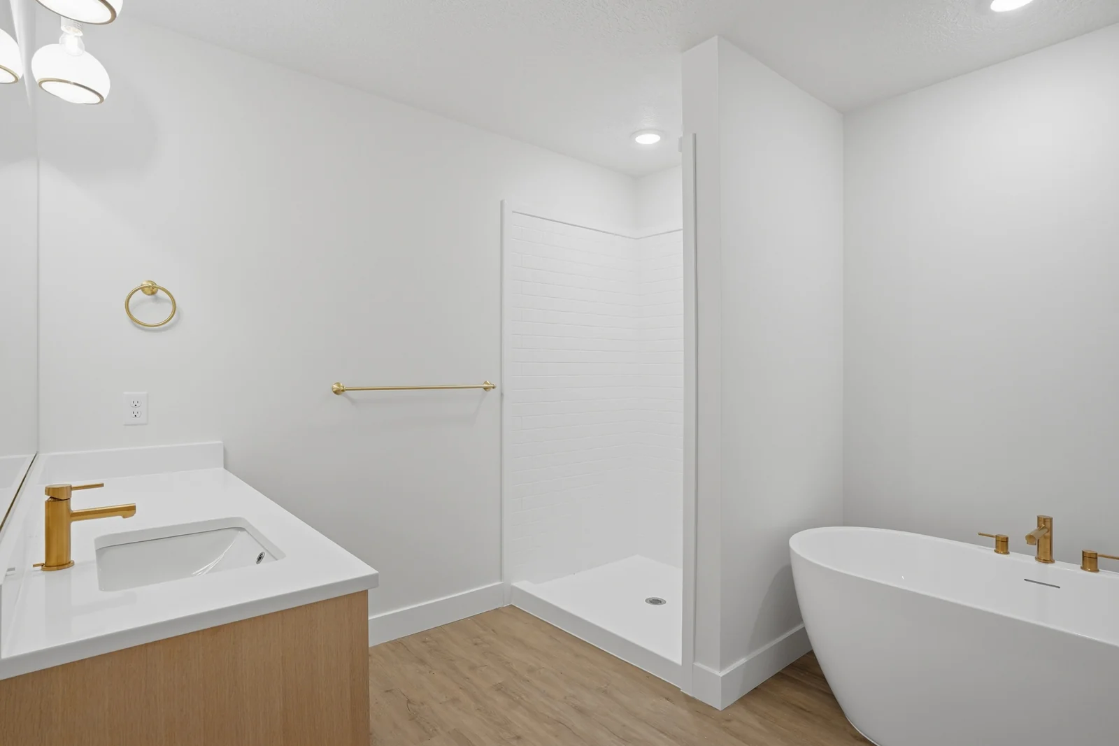 Bathroom with a wood vanity, freestanding tub, tiled shower, and gold-toned fixtures in Olympic BH08, American Fork.