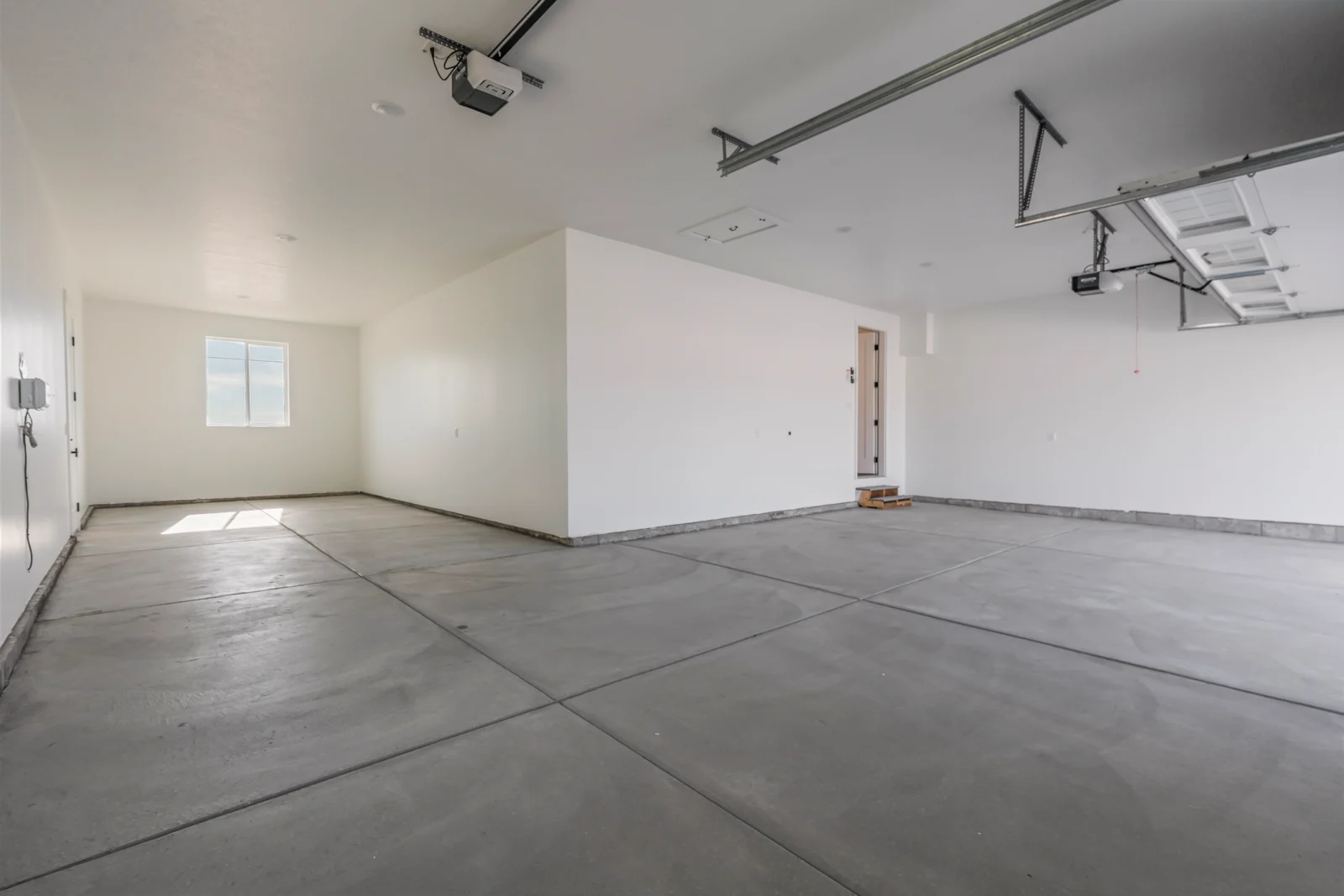Garage interior with concrete floor, open overhead door, door tracks, and neighborhood view outside at Chestnut MW311, Stansbury Park.