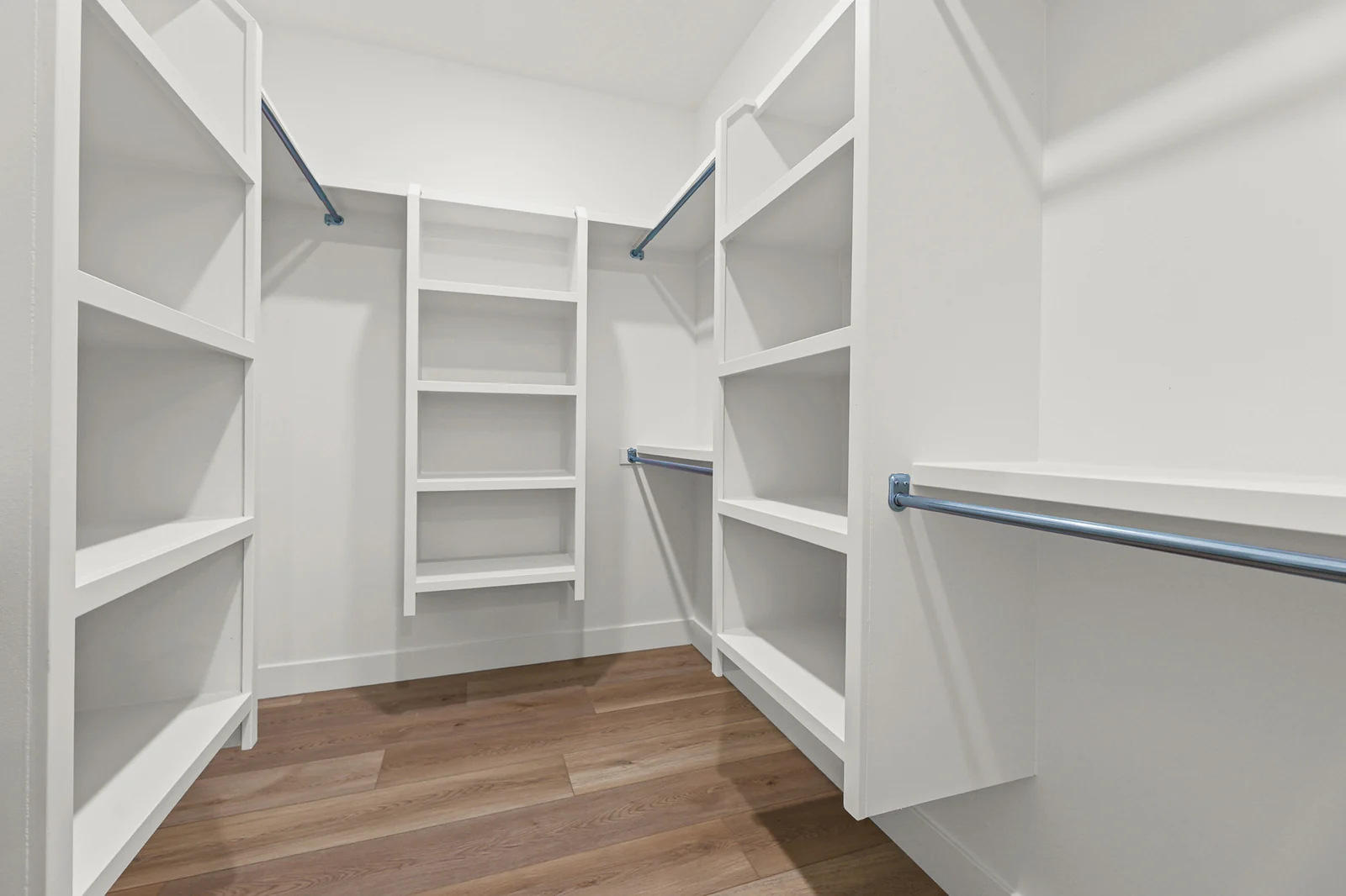 Walk-in closet with built-in white shelving, hanging rails, wood-look flooring, and recessed lighting in Hawthorne Modern, Ogden.