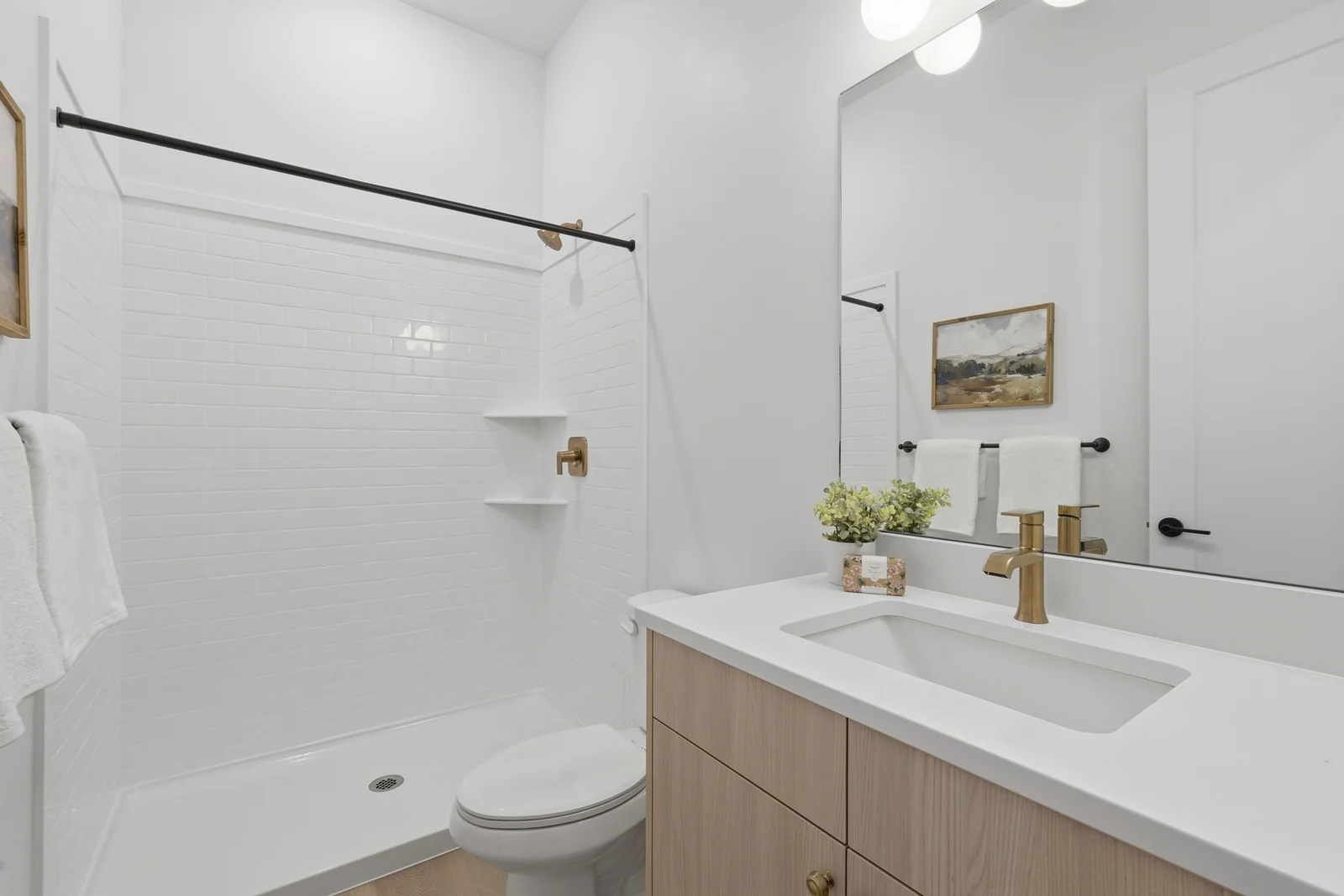 Bathroom with single vanity, toilet, tub-shower combination, black fixtures, and framed wall art in Chestnut Modern MW302, Stansbury Park.