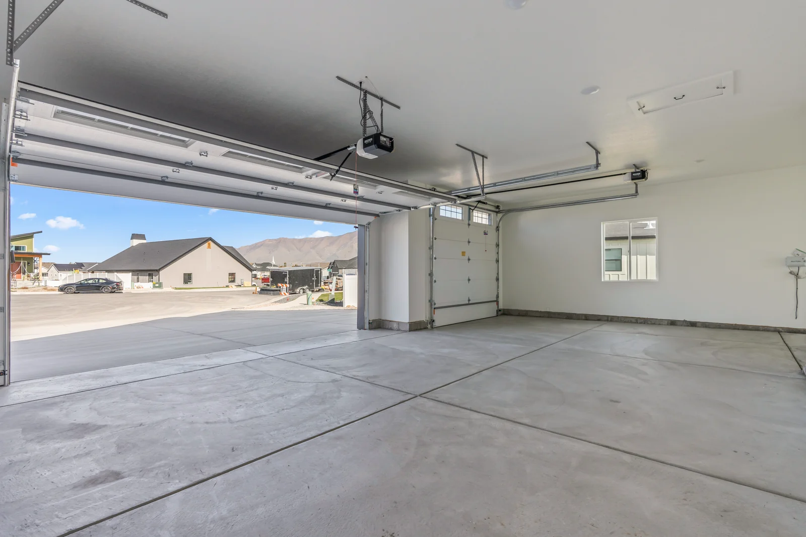 Covered rear patio with concrete slab, timber posts, windows, and sliding glass doors under roofline at Chestnut MW311, Stansbury Park.