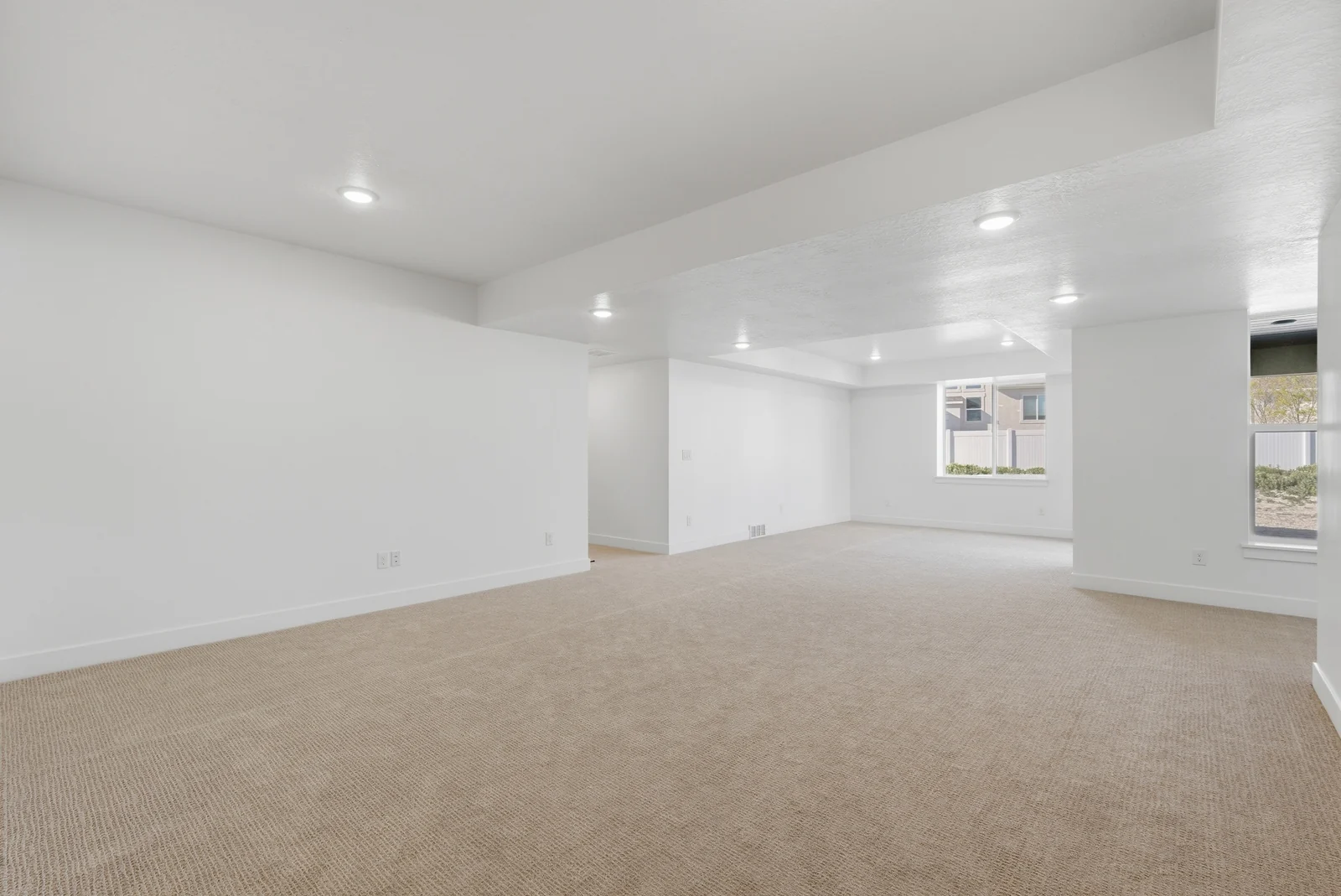 Open carpeted room with recessed lighting, white walls, support columns, windows, and adjoining doorways in Chestnut Modern MW302, Stansbury Park.