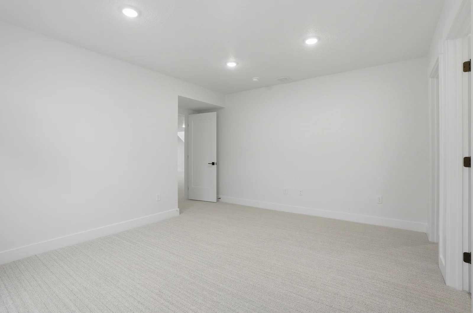 Unfurnished lower-level room with recessed lights, neutral carpet, white walls, and interior doorway in Olympic BH08, American Fork.
