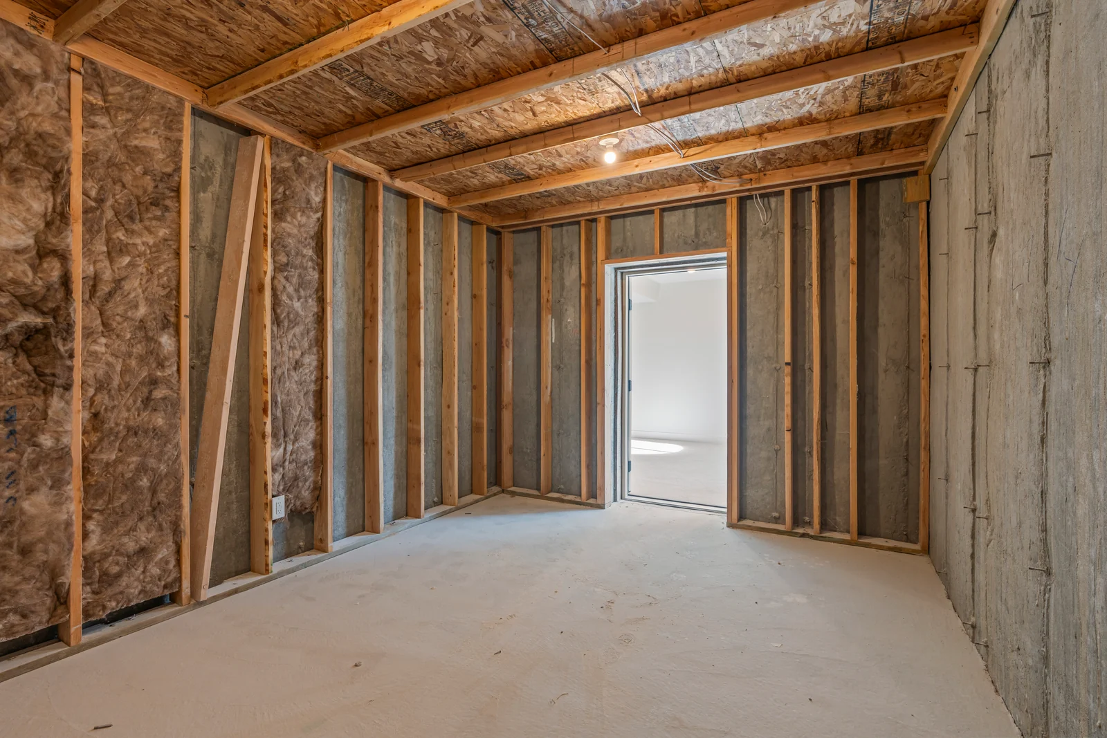 View along the covered rear patio showing timber posts, sliding glass door, exterior windows, and concrete slab at Chestnut MW311, Stansbury Park.