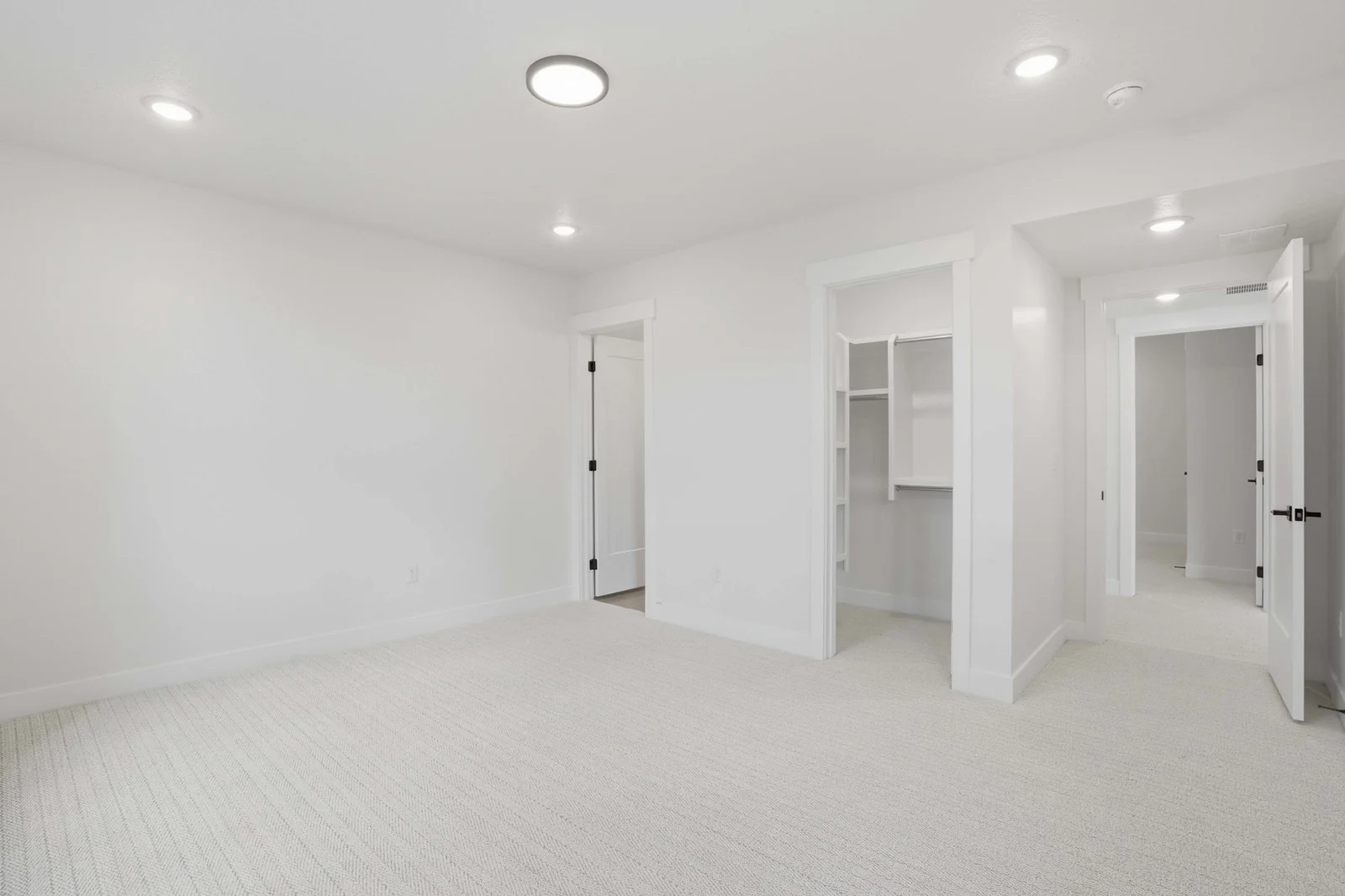 Unfurnished bedroom with pale carpet, recessed lights, white doors, and a visible closet storage niche in the Denali model, American Fork.